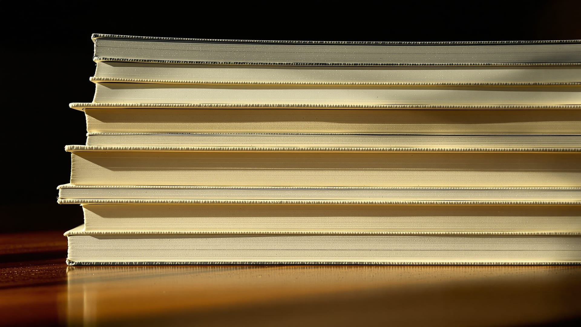 A stack of thirteen books beside an armchair